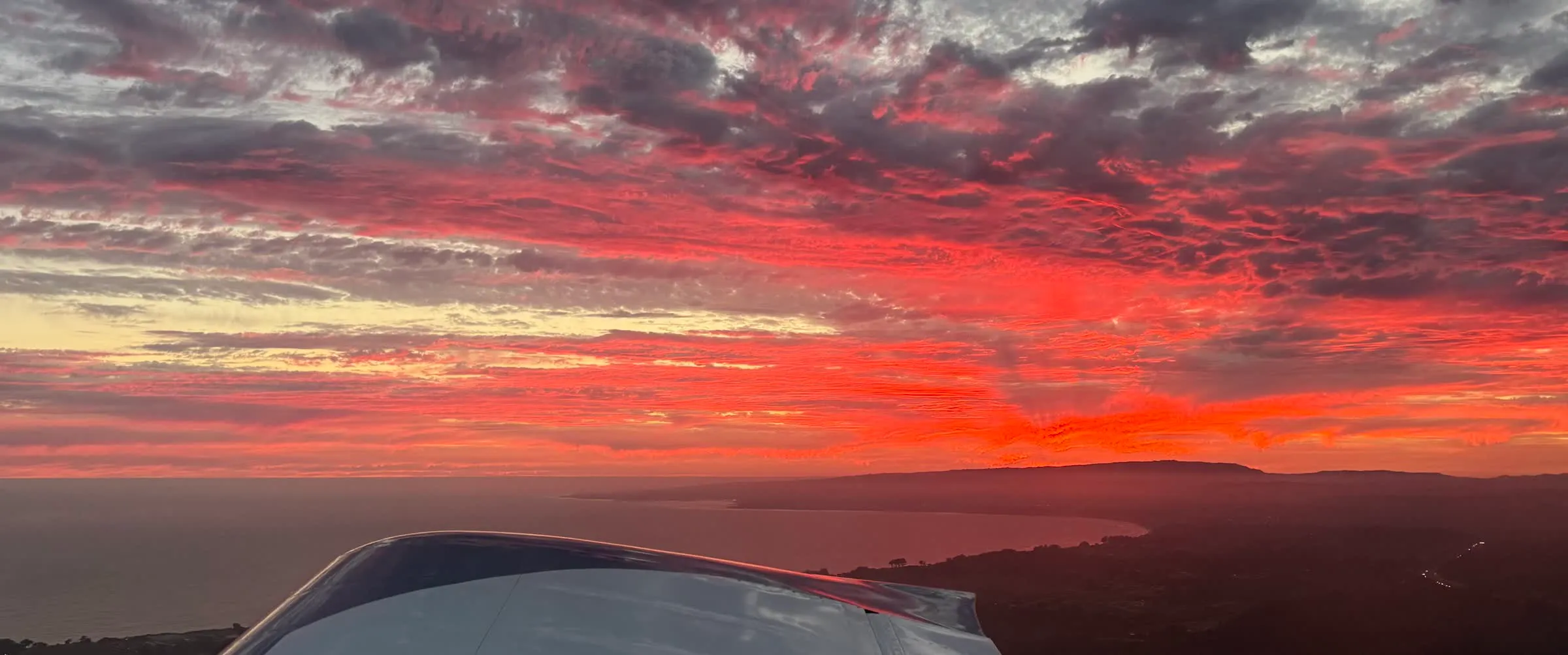 Sunset over the coast seen from a small plane's wingtip